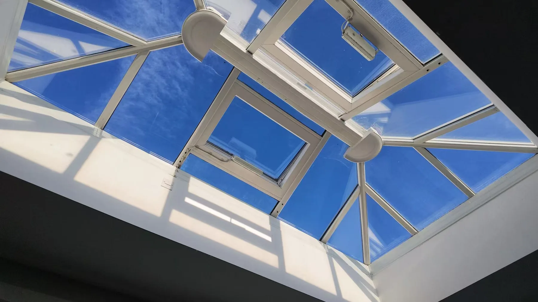 A bright blue sky framed by glass and white lines.